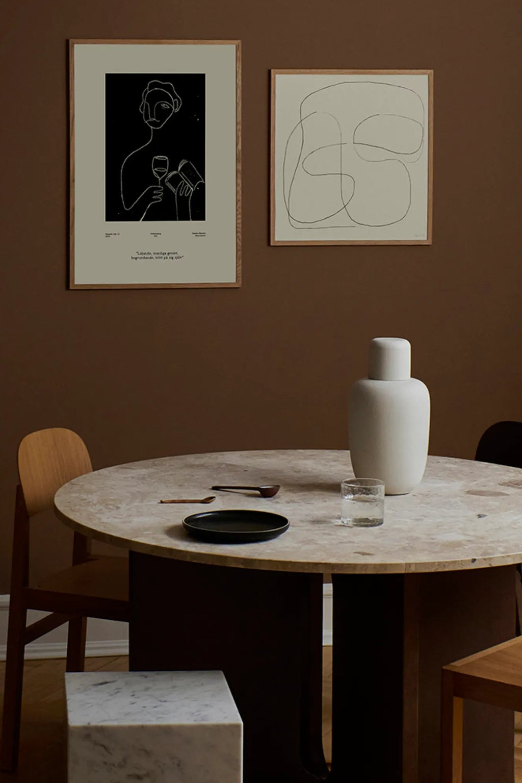 The Poster Club Genius, a minimalist abstract line art print featuring a continuous white line drawing of a figure holding a wine glass and a book, set against a deep black background with a light grey border.