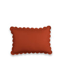 Rectangular orange pillow with scalloped edge on a white background