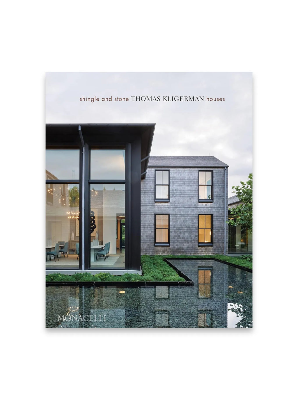 Book Shingle and Stone, a hardcover architectural design book featuring a modern house with dark shingle siding, large glass windows, and a reflecting pool. This premium coffee table book is ideal for architects, interior designers, and homeowners seeking inspiration for luxury home design.