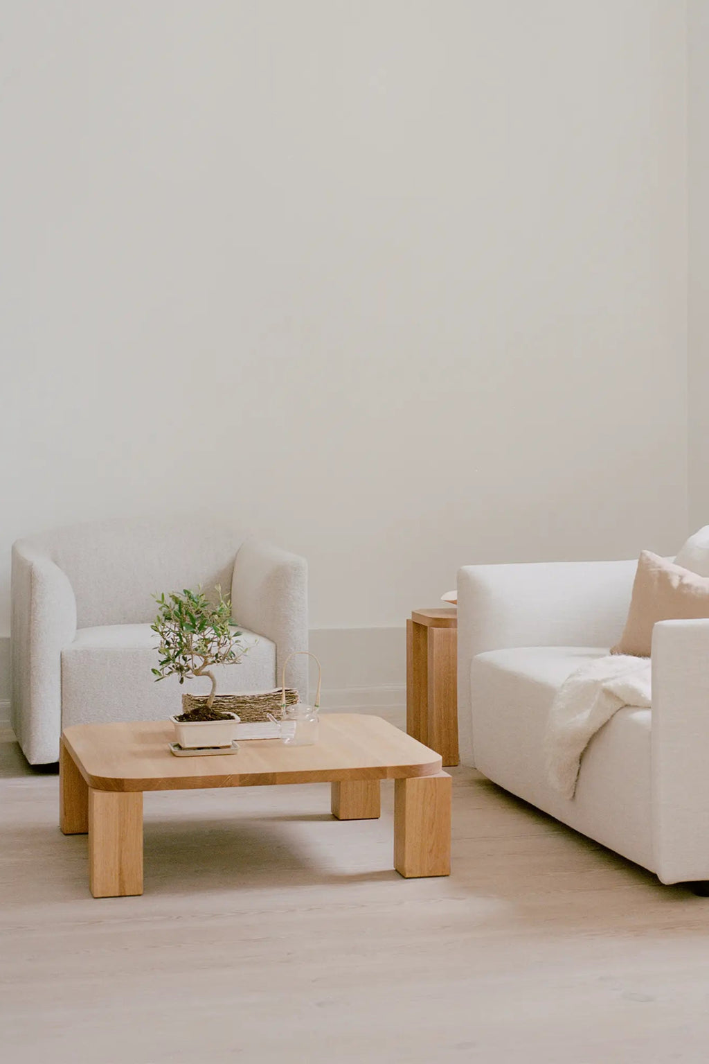 New Works Shore Lounge Chair - Extended Base, a contemporary lounge chair upholstered in a soft cream bouclé fabric with a plush textured finish and distinctive rounded silhouette. Its unique extended base design and organic modern lines make it a perfect minimalist armchair for a modern living room or cozy bedroom accent.