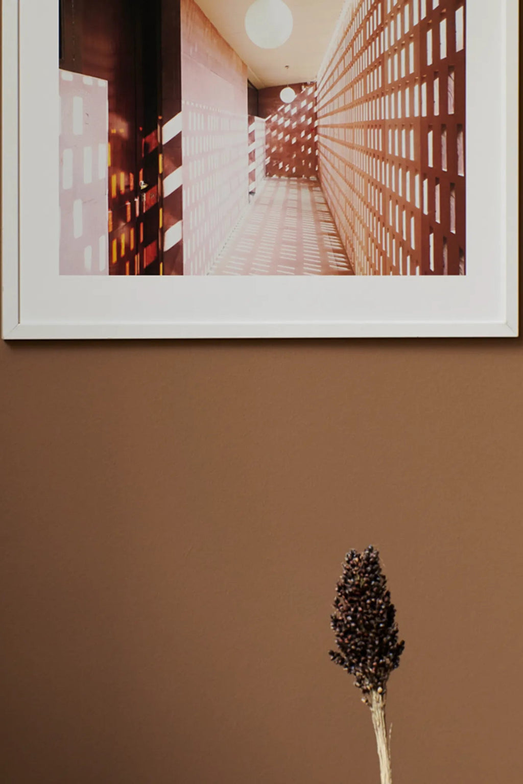 The Poster Club Lights, a modern architectural photography print capturing a long hallway with terracotta-toned perforated walls and strong light and shadow patterns, illuminated by spherical white ceiling lights.