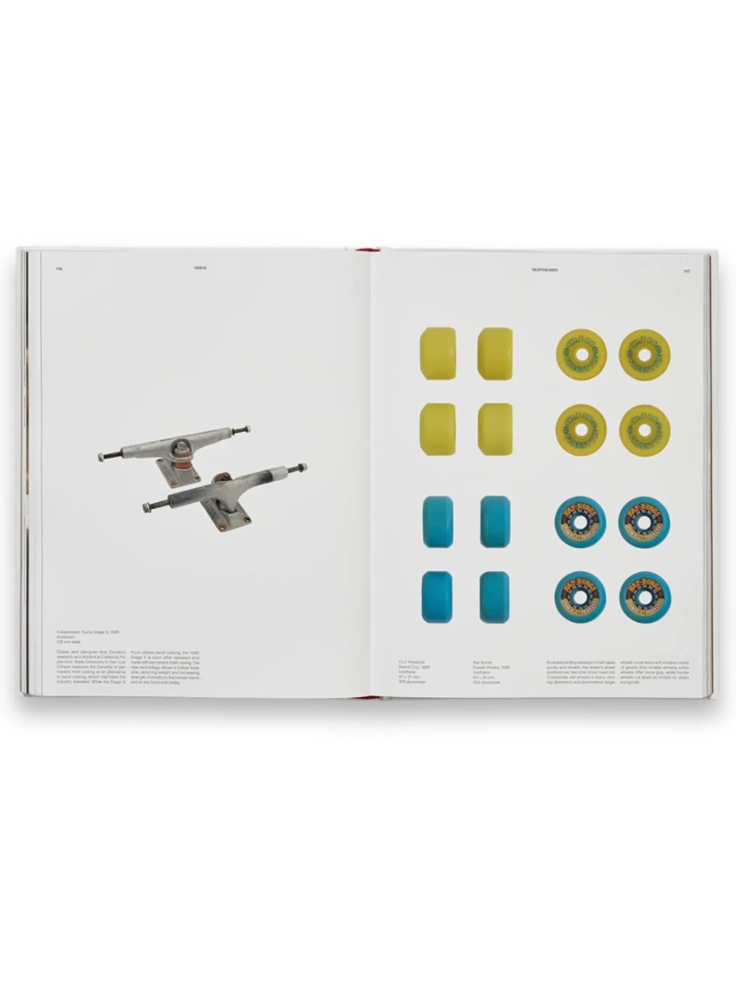 Book Skateboard, an open book displaying various skateboard components including two silver trucks and sets of yellow and blue wheels, both plain and with graphic designs. This informative book is perfect for skateboarding enthusiasts and collectors interested in the history and evolution of skateboard parts.