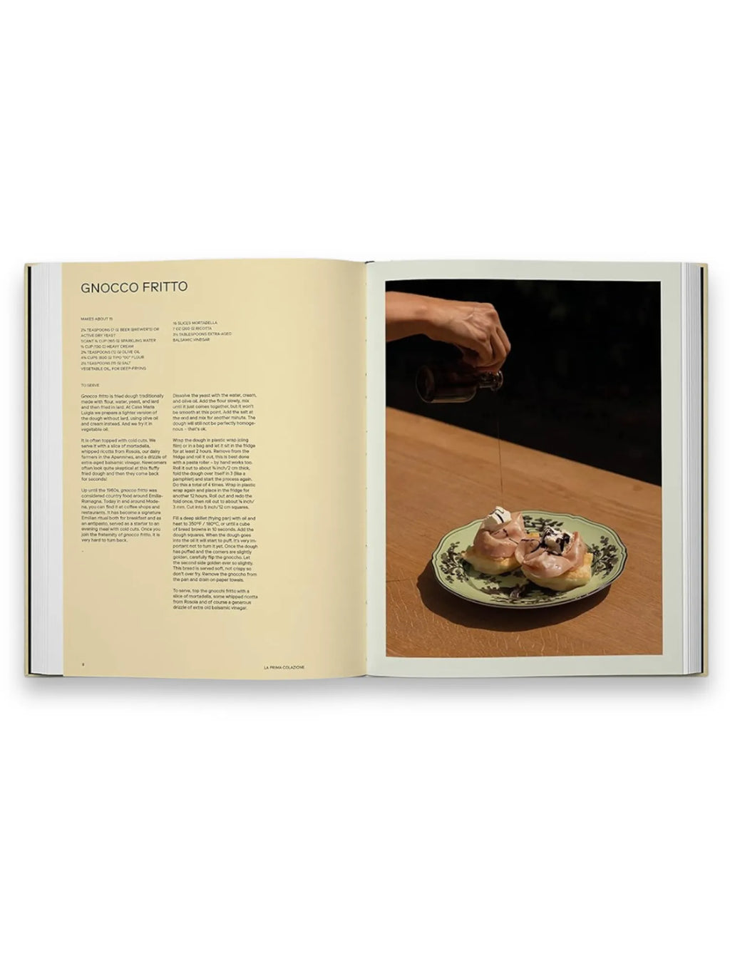 Book Slow Food, Fast Cars, featuring an open page with a "Gnocco Fritto" recipe, ingredients, and preparation instructions on the left. The right page displays a vibrant food photograph of a hand drizzling balsamic vinegar onto two pieces of gnocco fritto topped with mortadella and ricotta on a decorative green plate, set on a warm wooden table. This visually appealing cookbook is perfect for home chefs and culinary enthusiasts seeking authentic, modern Italian recipes.
