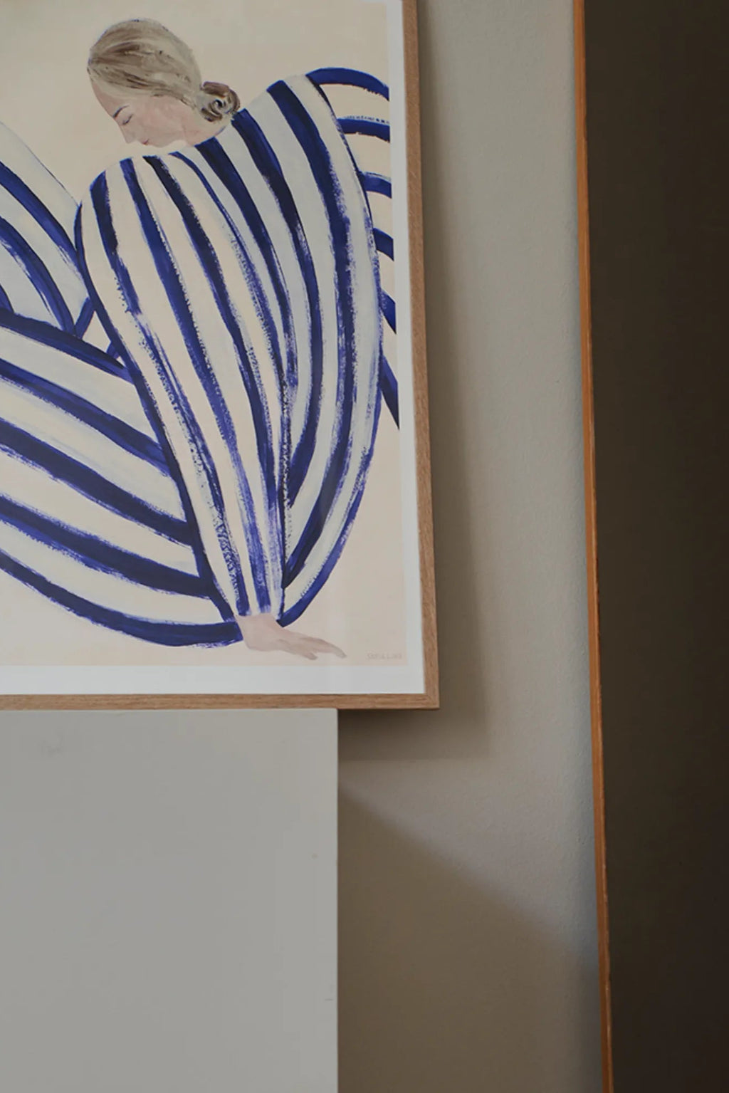The Poster Club Blue Stripe At Concorde, a modern abstract art print depicting an elegant figure draped in bold royal blue and cream stripes with visible brushstroke texture, presented in a light natural oak frame. This contemporary wall art is perfect for adding a coastal, minimalist, or Mediterranean aesthetic to living rooms, bedrooms, or a curated gallery wall.