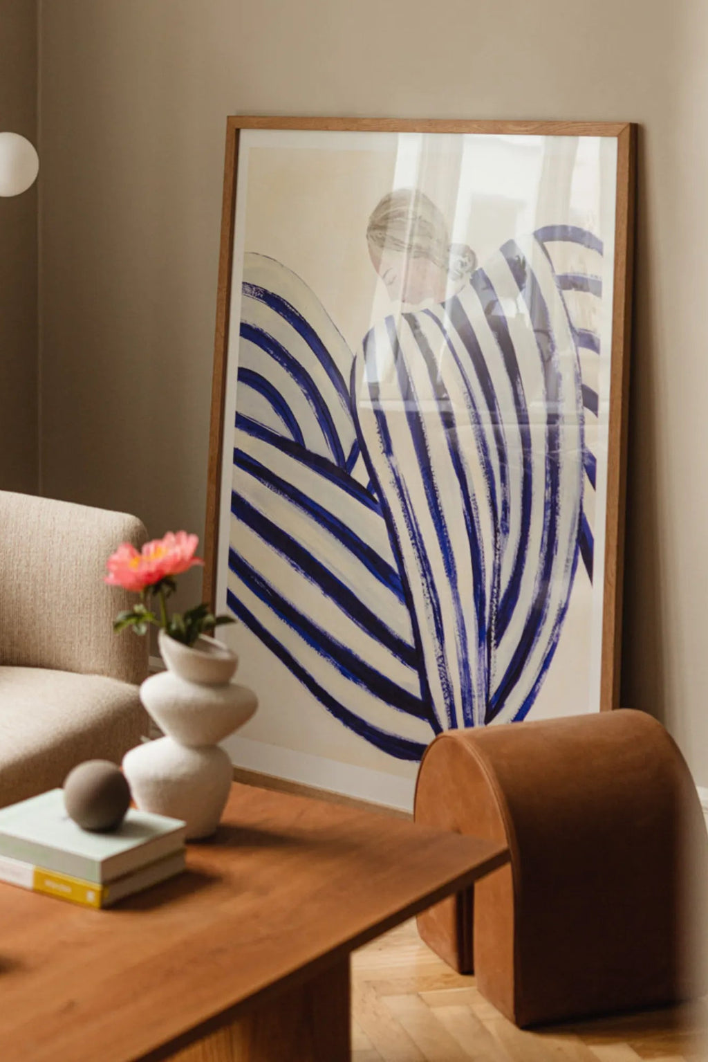The Poster Club Blue Stripe At Concorde, a contemporary abstract art print featuring bold navy blue brushstroke stripes creating organic, flowing shapes on a warm cream background, subtly suggesting a figural form. This minimalist wall art is presented in a natural oak frame, perfect for modern living rooms, Scandinavian bedrooms, or a stylish gallery wall.