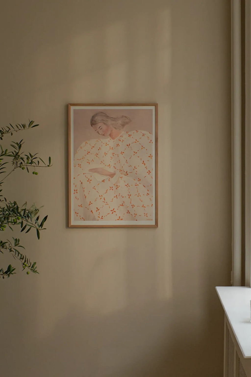 The Poster Club Secret Notes, a contemporary illustration art print depicting a woman in a white dress adorned with a delicate orange floral pattern, presented against a soft muted peach-pink background and framed in.
