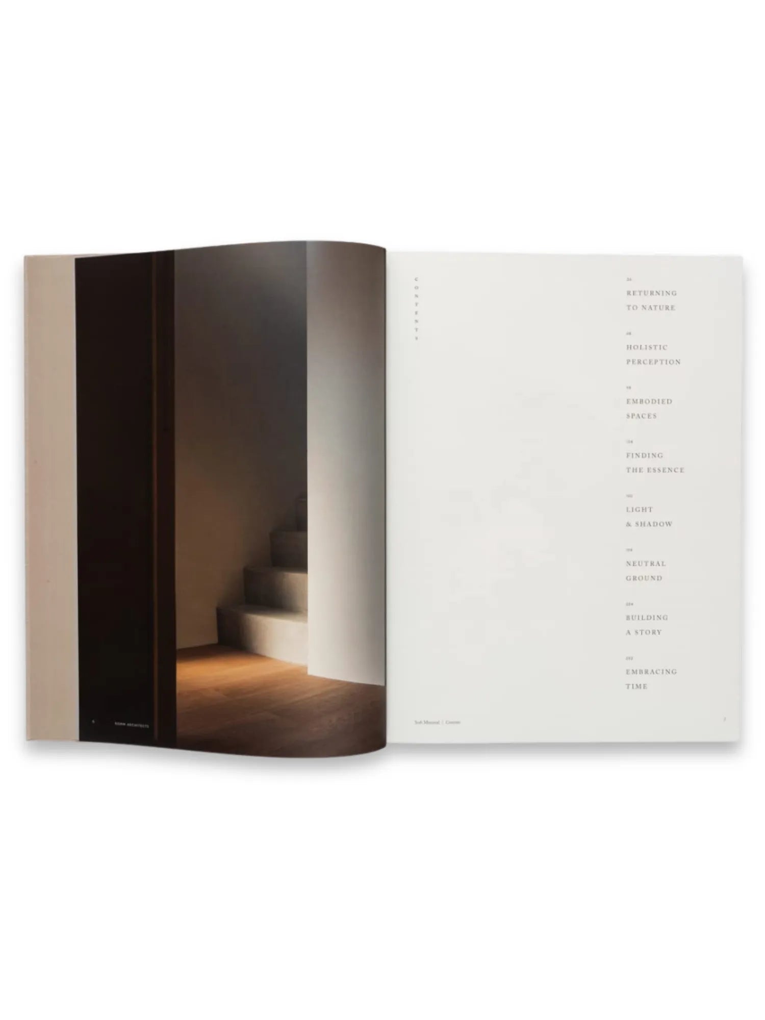 Book Soft Minimal – By Norm Architects, an open architectural design book displaying a minimalist interior photo of a dark hallway with sunlit wooden floors and concrete stairs, alongside a clean table of contents page. This premium coffee table book offers design inspiration for modern architecture and interior design enthusiasts.