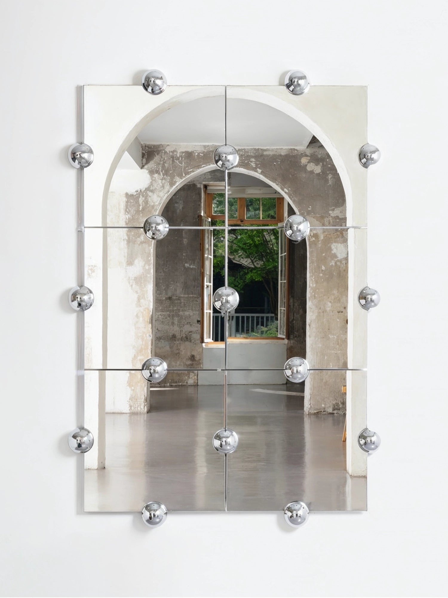 Moustache Sphera Crystal Palace L Vertical Mirror, a striking modular mirror featuring six square panels and chrome spherical fasteners, reflecting an arched doorway and window.