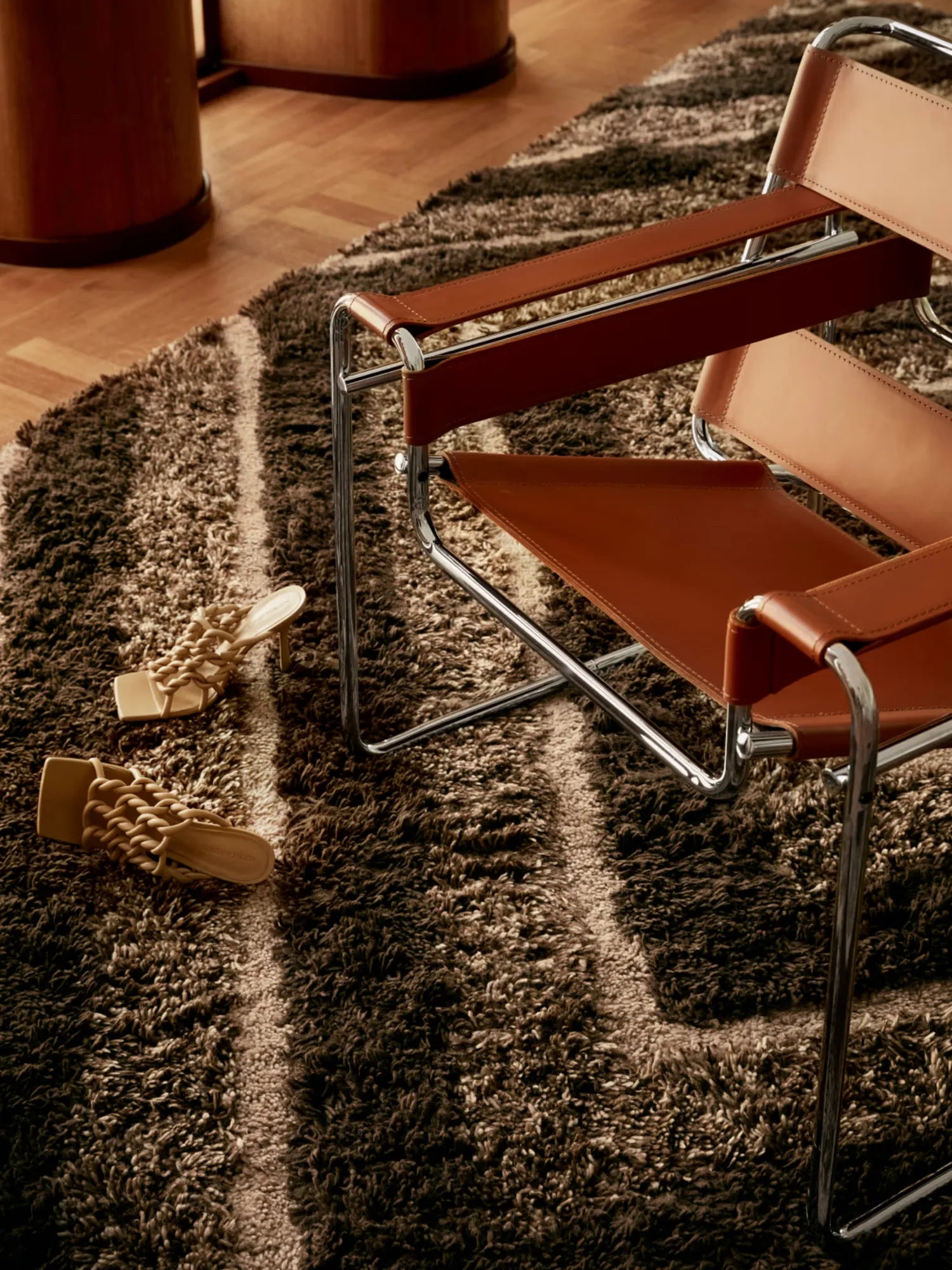 Tinted Objects Stenborg Wool Rug, a luxurious deep pile shag rug with an organic brown and beige striped pattern. This high-quality floor covering is perfect for adding warmth and sophisticated texture to any modern living space or bedroom.