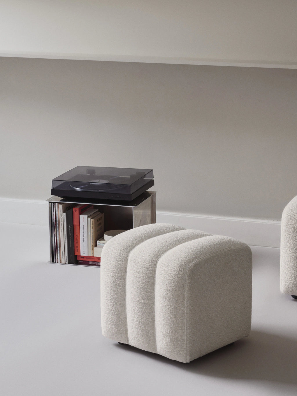NORR11 Studio Pouf, a cream-colored organic modern pouf upholstered in plush bouclé fabric, featuring a soft textured finish and three distinct vertical channels for a fluted design. This contemporary bouclé ottoman is perfect as accent seating or a stylish footrest for minimalist living rooms, Scandinavian bedrooms, or cozy reading nooks.