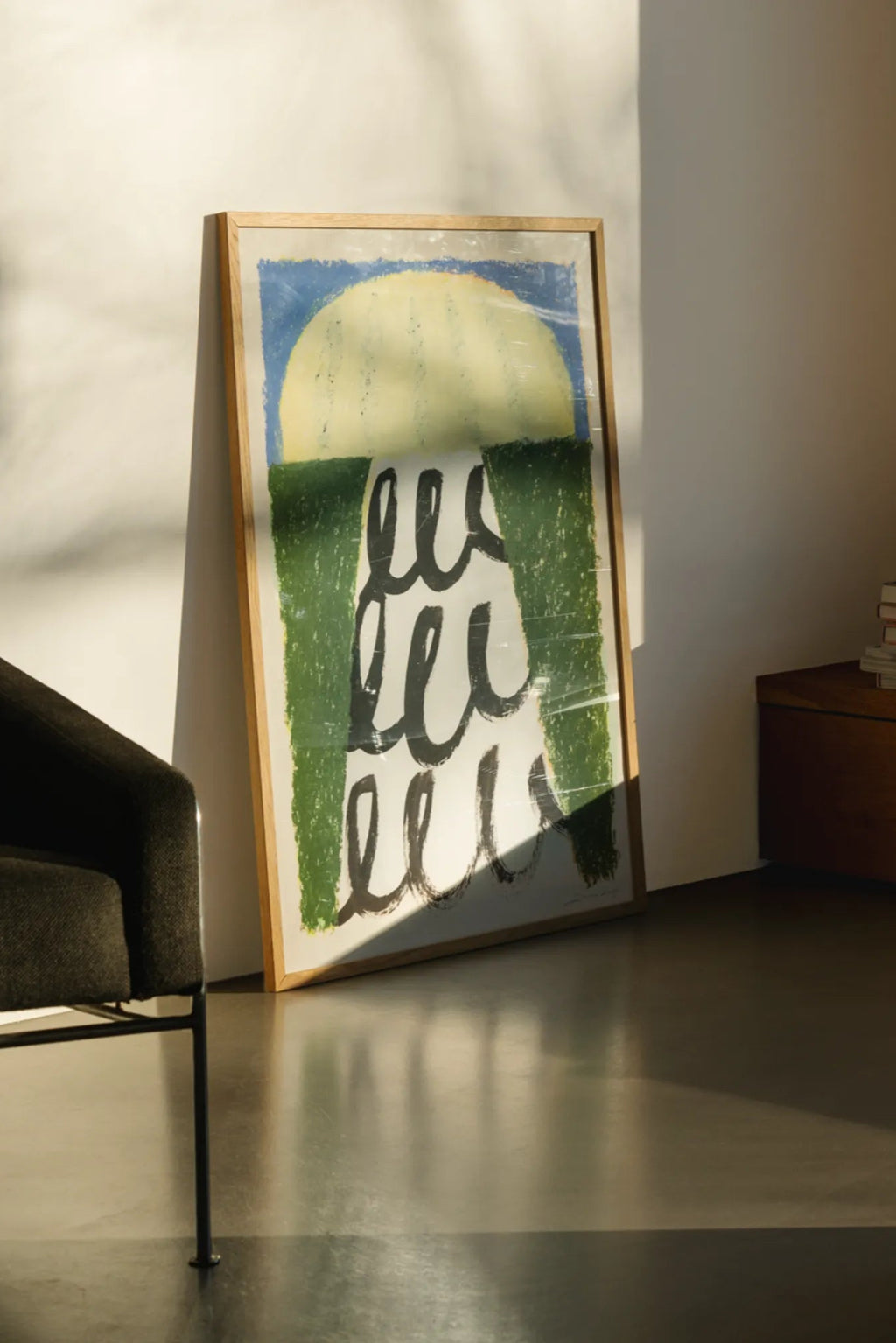 The Poster Club Energize, an abstract art print featuring a large textured yellow semi-circle above dark green blocks and bold black wavy lines on a white background, with a blue upper border. This vibrant contemporary poster is presented in a light natural oak frame. Perfect for modern living rooms, bedrooms, or gallery walls seeking a colorful abstract touch.