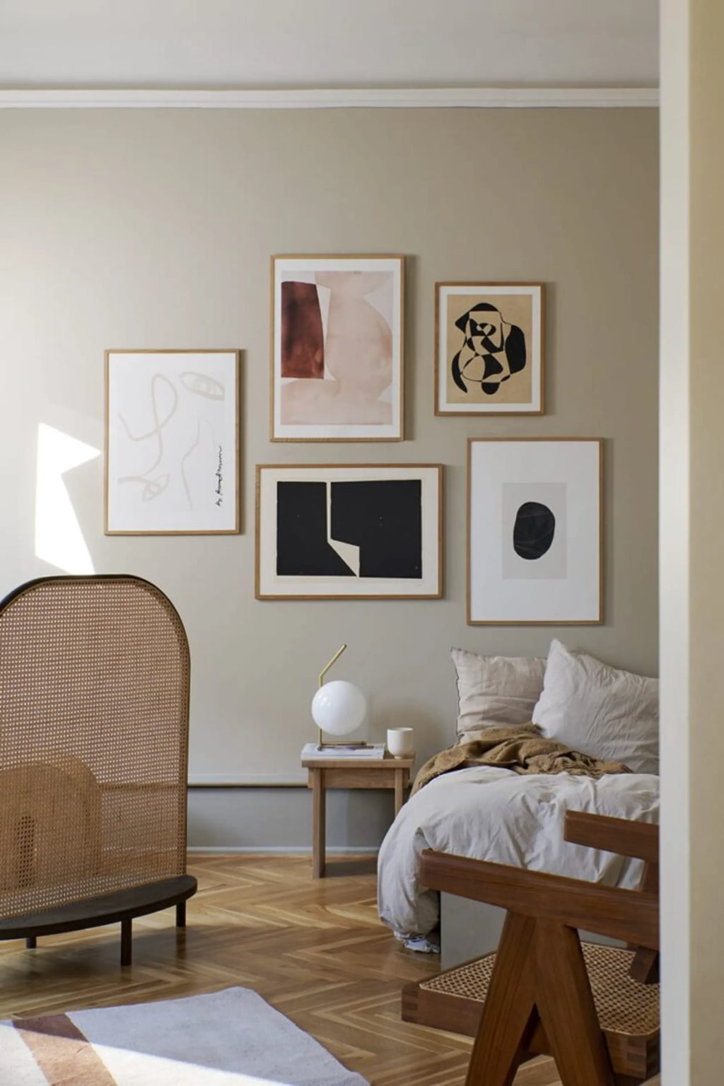 The Poster Club Facesing - Art Print, a stylish gallery wall featuring five modern abstract artworks in natural wood frames on a warm beige wall. This collection of contemporary wall art is ideal for decorating a sophisticated bedroom or living space.