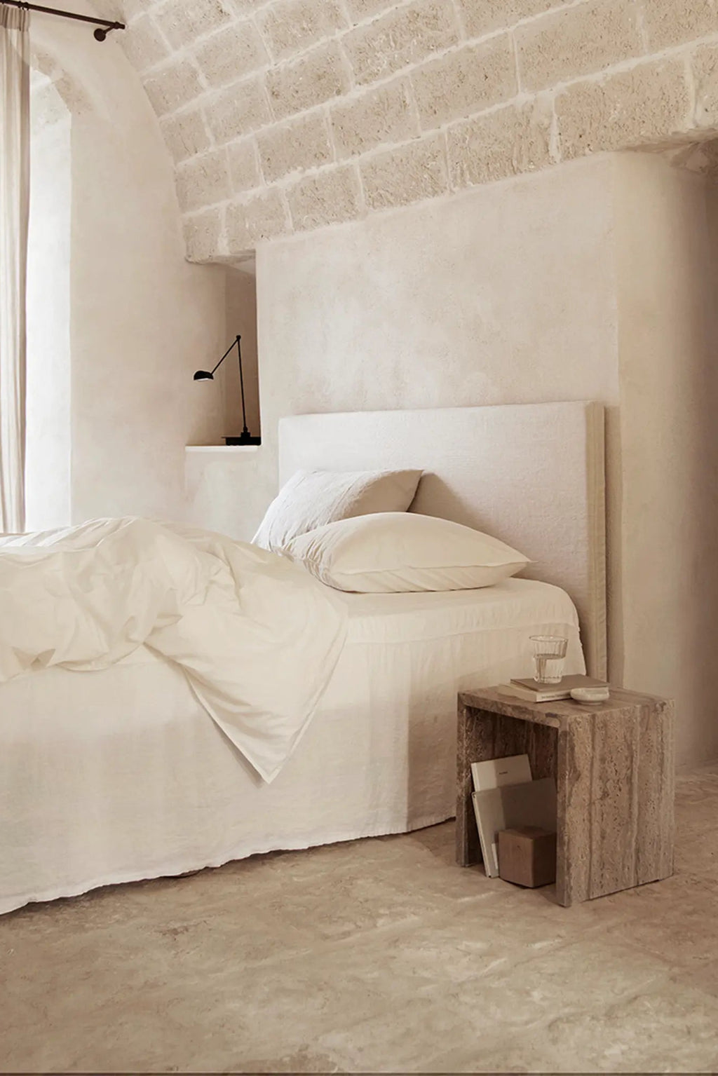 Tine K Cube Travertine Table, a minimalist cube side table crafted from natural, light beige travertine with a distinctly porous and rough-hewn texture, offering an earthy, organic modern aesthetic. This versatile travertine nightstand provides open storage, perfect for a wabi-sabi inspired bedroom or a contemporary living room accent.