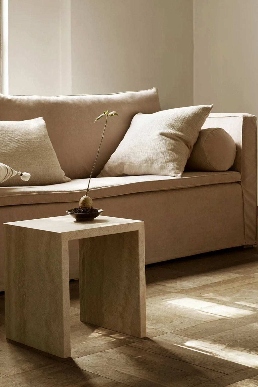 Tine K Cube Travertine Table, a modern minimalist side table crafted from solid natural travertine stone with a light beige, creamy hue and subtle organic texture. Its distinct U-shaped, open cube design provides a brutalist-inspired yet elegant accent, perfect as a living room end table or contemporary bedside table in organic modern or Scandinavian spaces.