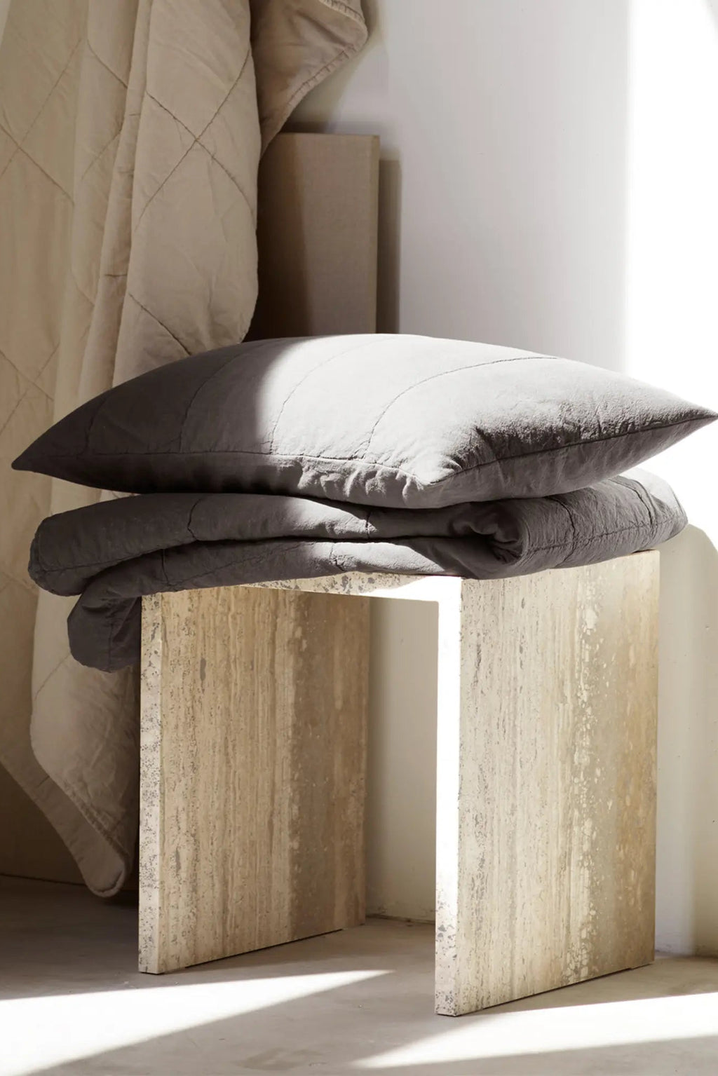 Tine K Cube Travertine Table, a minimalist cube side table crafted from natural cream travertine stone, featuring a raw, porous texture and unique organic veining. Its clean, geometric rectangular prism silhouette embodies an organic modern or brutalist aesthetic. Perfect as a contemporary accent table for living rooms, a chic bedroom nightstand, or a sophisticated pedestal for shelf styling.