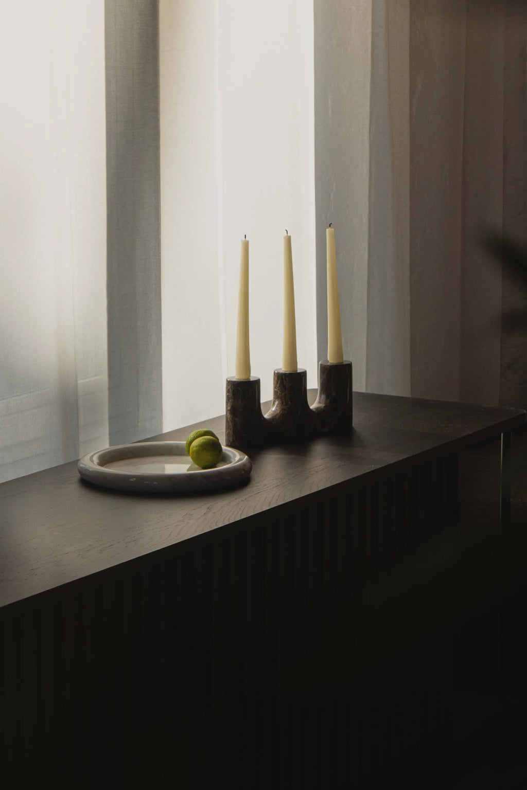 TAMO Trilo Candle Holder in lifestyle setting, featuring a premium dark brown marbled stone candelabra with three off-white tapered candles. Ideal for elegant home decor.
