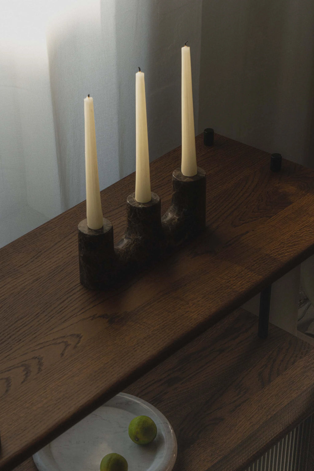 TAMO Trilo Candle Holder, a premium dark brown marble triple candle holder with three cream tapered candles, displayed on a rich wood surface. Ideal for elegant home decor.