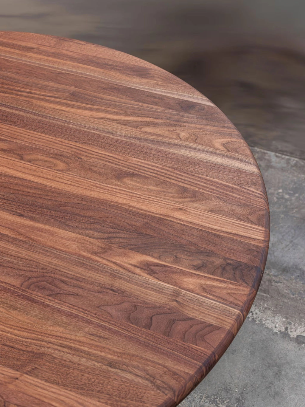 Tinted Objects Sanders Round Dining Table, featuring a rich, dark brown wooden tabletop with prominent, natural wood grain patterns and a smooth, polished finish. This elegant, modern dining table is perfect for those seeking a stylish and durable centerpiece for their contemporary dining room.