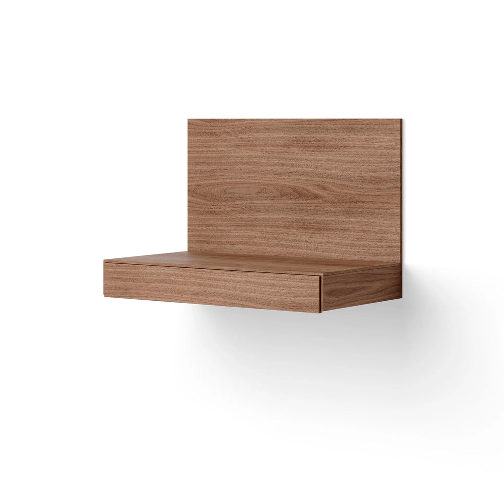 New Works Tana Wall Mounted Desk, a modern minimalist floating desk featuring a rich warm brown walnut wood veneer with a prominent grain, a sleek rectangular back panel, and a seamlessly integrated, flush drawer.