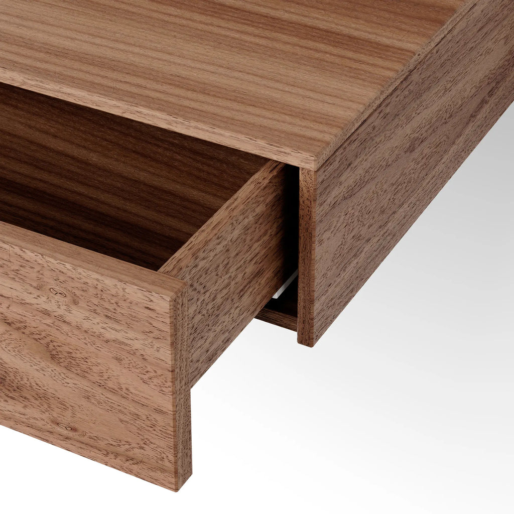 New Works Tana Wall Mounted Desk, a sleek modern minimalist wall-mounted desk crafted from solid warm brown wood, featuring a single smooth-gliding pull-out drawer with clean, handleless lines. This Scandinavian-inspired floating desk is ideal for small home offices, bedrooms, or entryways, offering discreet storage and a contemporary aesthetic.