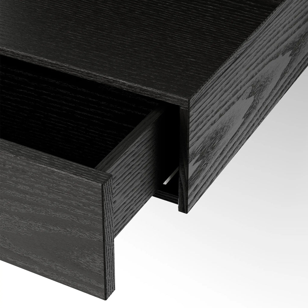 New Works Tana Wall Mounted Desk, a sleek modern minimalist floating desk crafted from dark black stained oak wood with a distinctive visible grain texture and a clean, rectangular silhouette. This contemporary wall-mounted desk features an integrated drawer for discreet storage, perfect for a Scandinavian home office, compact workspace, or stylish entryway console.