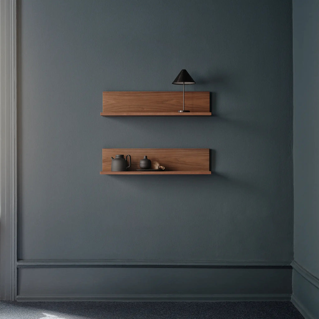 New Works Tana Wall Shelf, a modern minimalist floating wall shelf crafted from rich, warm solid walnut wood with a sleek rectangular silhouette and an integrated back panel. This contemporary wooden display shelf offers versatile storage and elegant shelf styling for Scandinavian living rooms, bedrooms, or home offices.