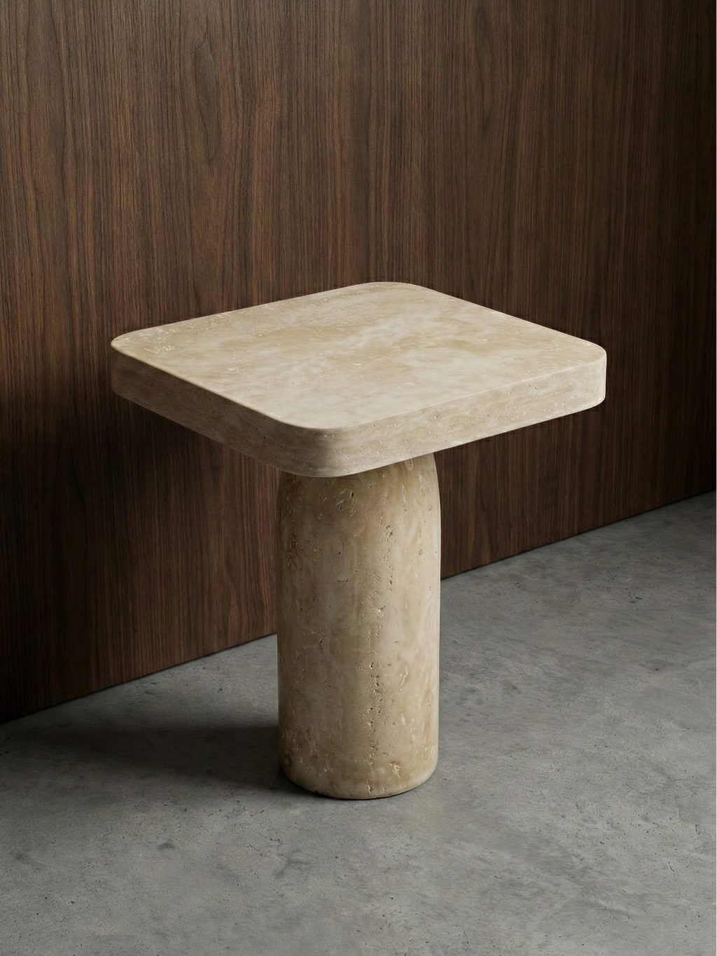 TCL Studios Tau Travertine Side Table, a light beige natural travertine side table featuring a thick square top with gently rounded corners and a robust cylindrical base, all crafted from porous, raw-cut natural stone. This organic modern accent table, with its brutalist influence, is ideal for minimalist living rooms, contemporary bedrooms, or elegant entryways.