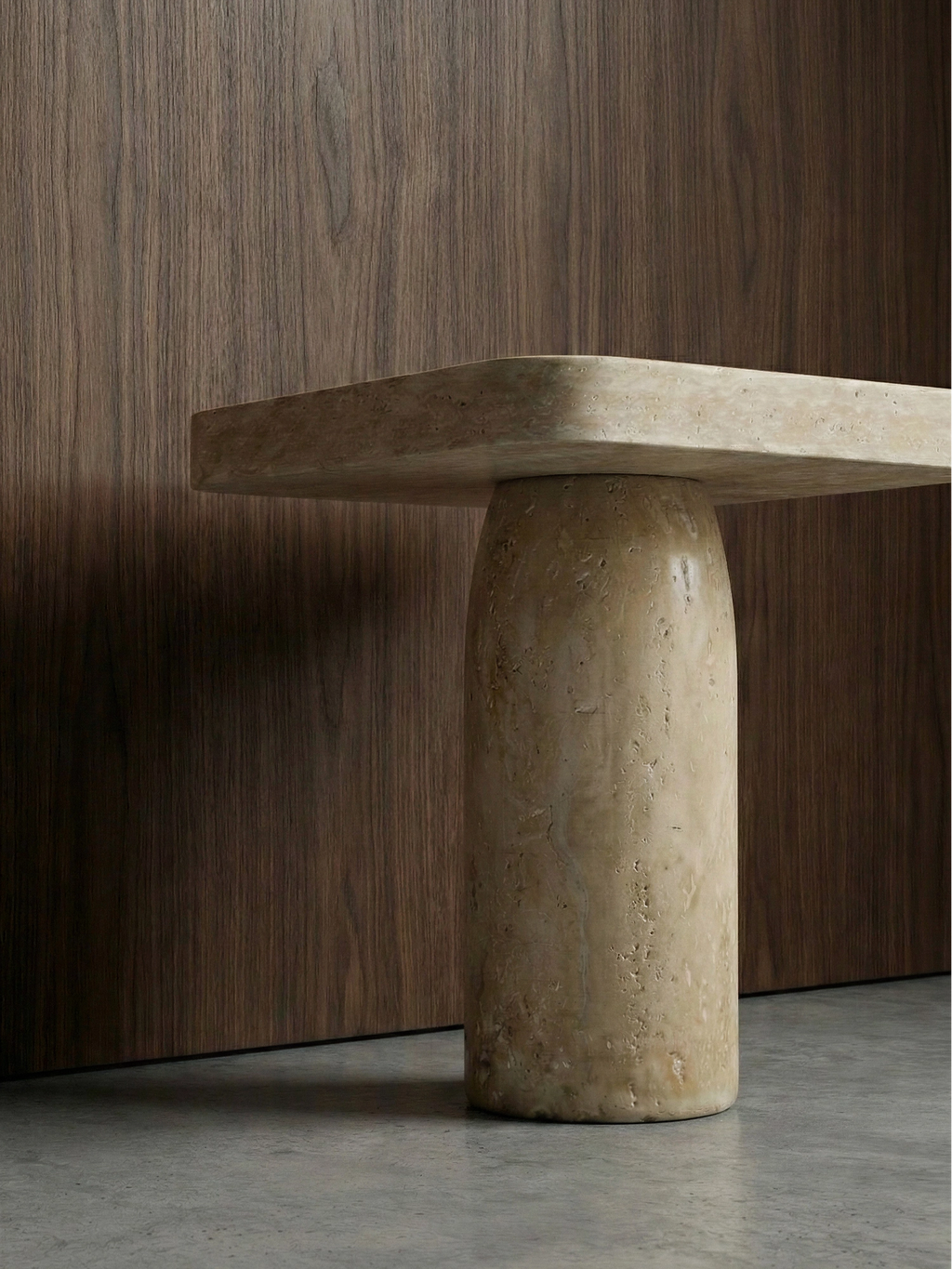 TCL Studios Tau Travertine Side Table, a minimalist organic modern side table crafted from natural light beige honed travertine, featuring a thick rectangular top with softly rounded edges and a robust cylindrical column base. Its sculptural form and earthy porous texture make it an ideal accent for contemporary living rooms or a sophisticated bedside table in brutalist or japandi interiors.