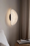 Tense Wall Lamp in black color illuminating a cozy bedroom