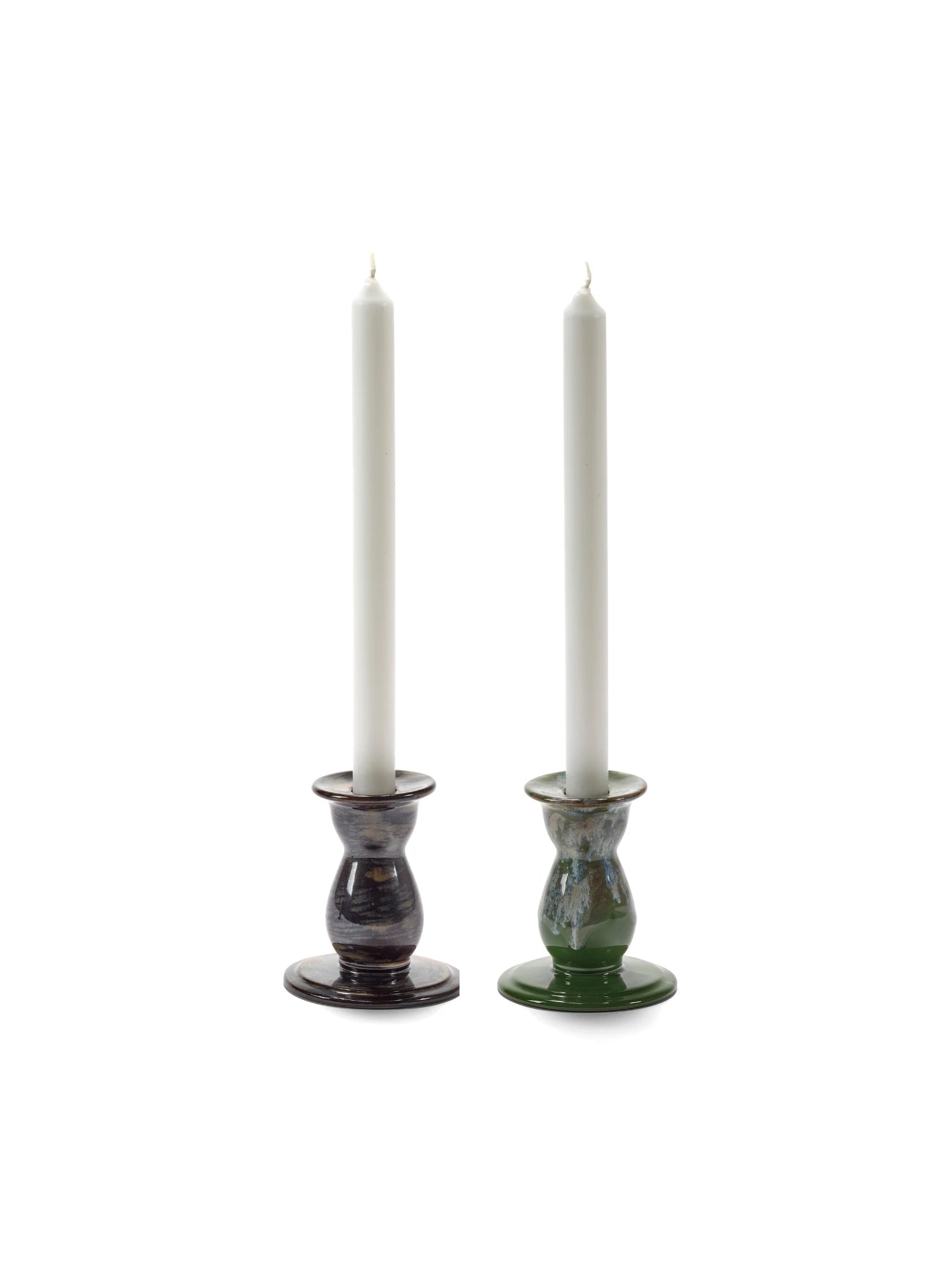 Two candle holders with white candles on a white background