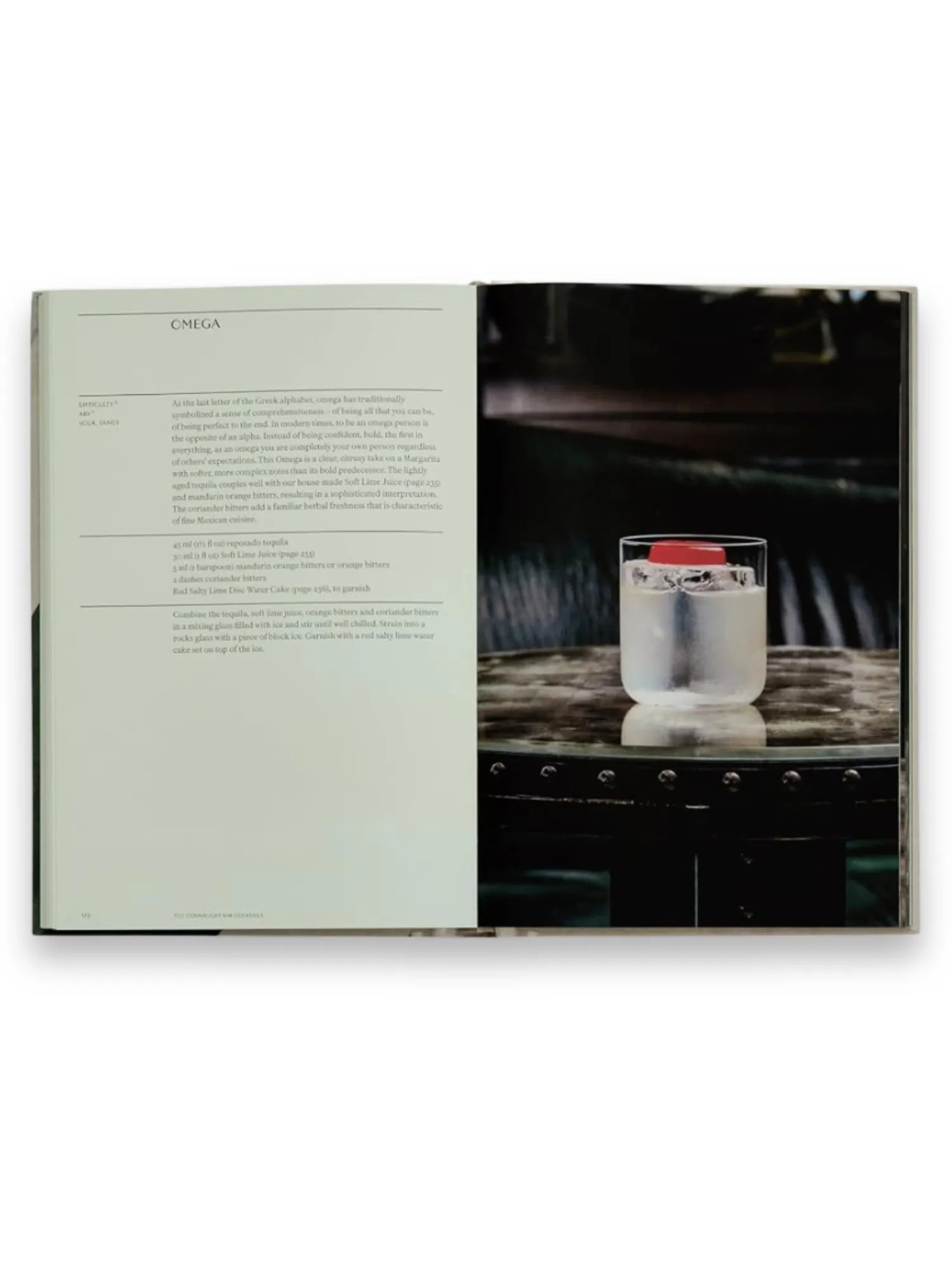 Book The Connaught Bar, an open high-quality cocktail recipe book displaying a detailed "Omega" cocktail recipe on the left page and a vibrant photo of the prepared drink on the right. This premium printed book is perfect for aspiring mixologists and cocktail enthusiasts.