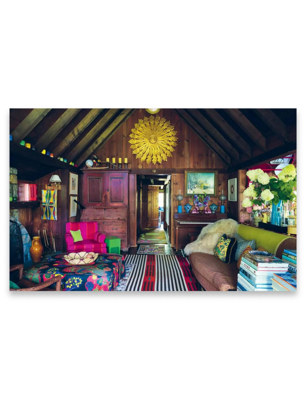 Book The Design Retreat, a vibrant living room interior with rustic wooden walls and ceiling beams, featuring colorful eclectic furnishings like a fuchsia armchair, a patterned ottoman, and a striped rug. This inspiring interior design book is ideal for home decorators and design enthusiasts seeking creative and unique decor ideas.