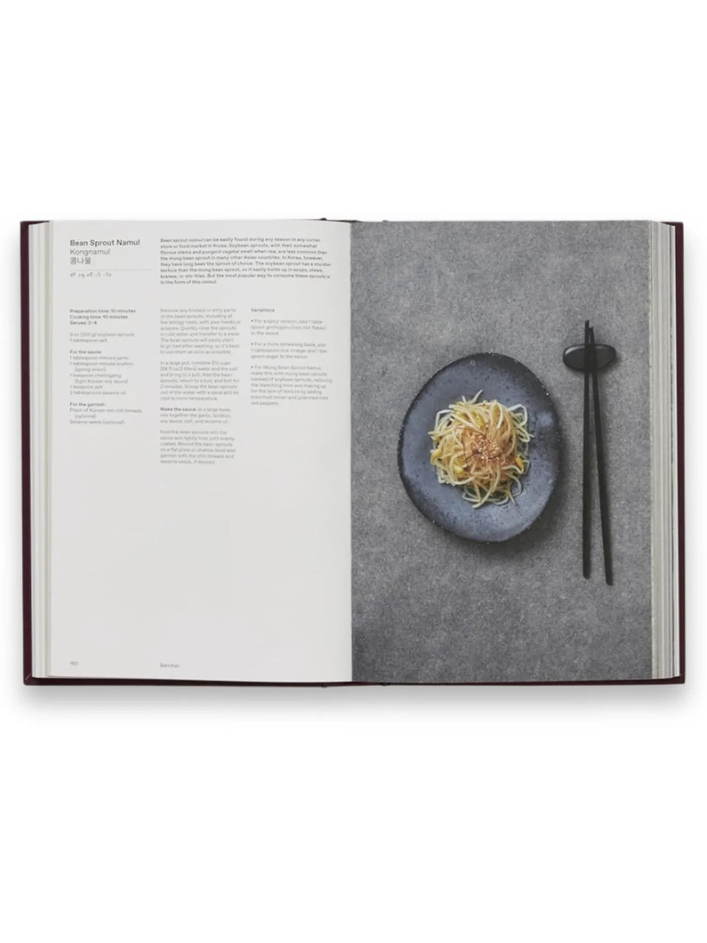 Book The Korean Cookbook, an open hardcover recipe book featuring a "Bean Sprout Namul" recipe with detailed text and a vibrant photo of the dish on a dark, textured plate with black chopsticks. This essential cookbook is perfect for home cooks eager to explore authentic Korean cuisine.
