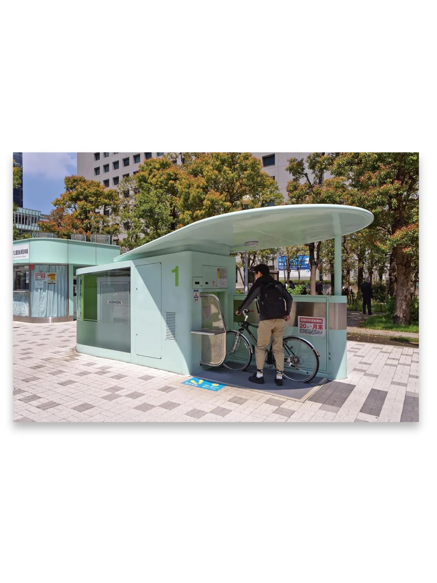 Book The Monocle Guide to Building Better Cities, featuring a stylish mint green modular bike parking station with a curved roof, set against a backdrop of lush green and autumn-colored trees and a modern building. This thought-provoking urban planning book is perfect for architects, city planners, and engaged citizens interested in sustainable city development.