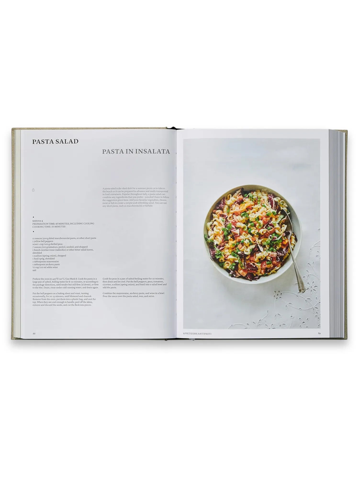 Book The Silver Spoon, open hardcover cookbook showcasing a vibrant "Pasta Salad" recipe with ingredients and instructions on the left page, and a colorful pasta salad dish in a white bowl with a silver spoon on a white embroidered tablecloth on the right. This essential Italian cooking guide is perfect for home chefs seeking authentic, delicious recipes.