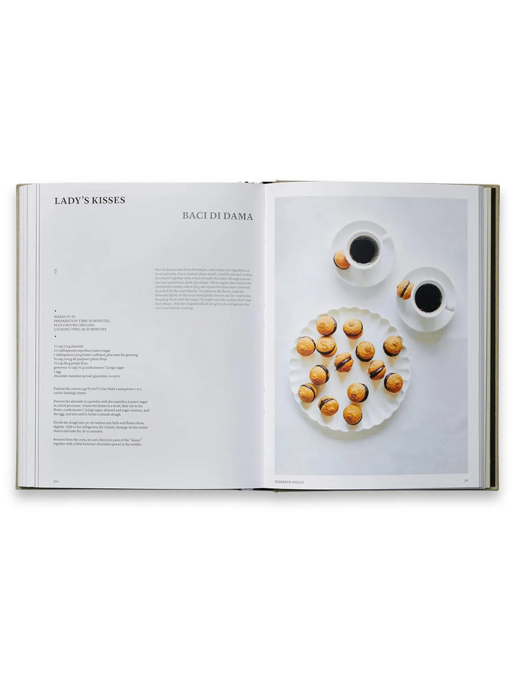 Book The Silver Spoon, open hardcover cookbook displaying a "Lady's Kisses" (Baci di Dama) recipe with rich text and a vibrant full-page photograph of golden-brown cookies filled with chocolate-hazelnut spread, artistically arranged on a scalloped white plate next to two cups of black coffee. This classic Italian cookbook is perfect for home bakers and culinary enthusiasts seeking authentic dessert recipes.