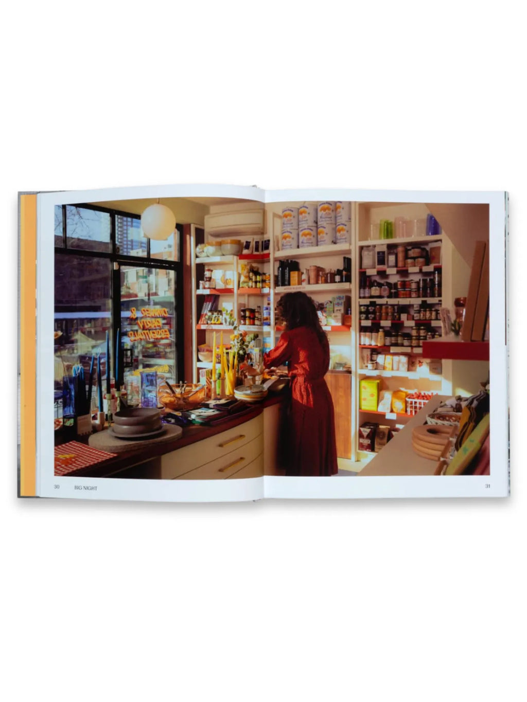 Book Think Big Shop Small, an open page spread featuring a vibrant photo of a woman in a red dress working in a cozy, well-stocked specialty food shop, showcasing various gourmet products on shelves and a counter with candles and dishes. This inspiring business book is perfect for aspiring entrepreneurs and small business owners seeking motivation and practical advice.