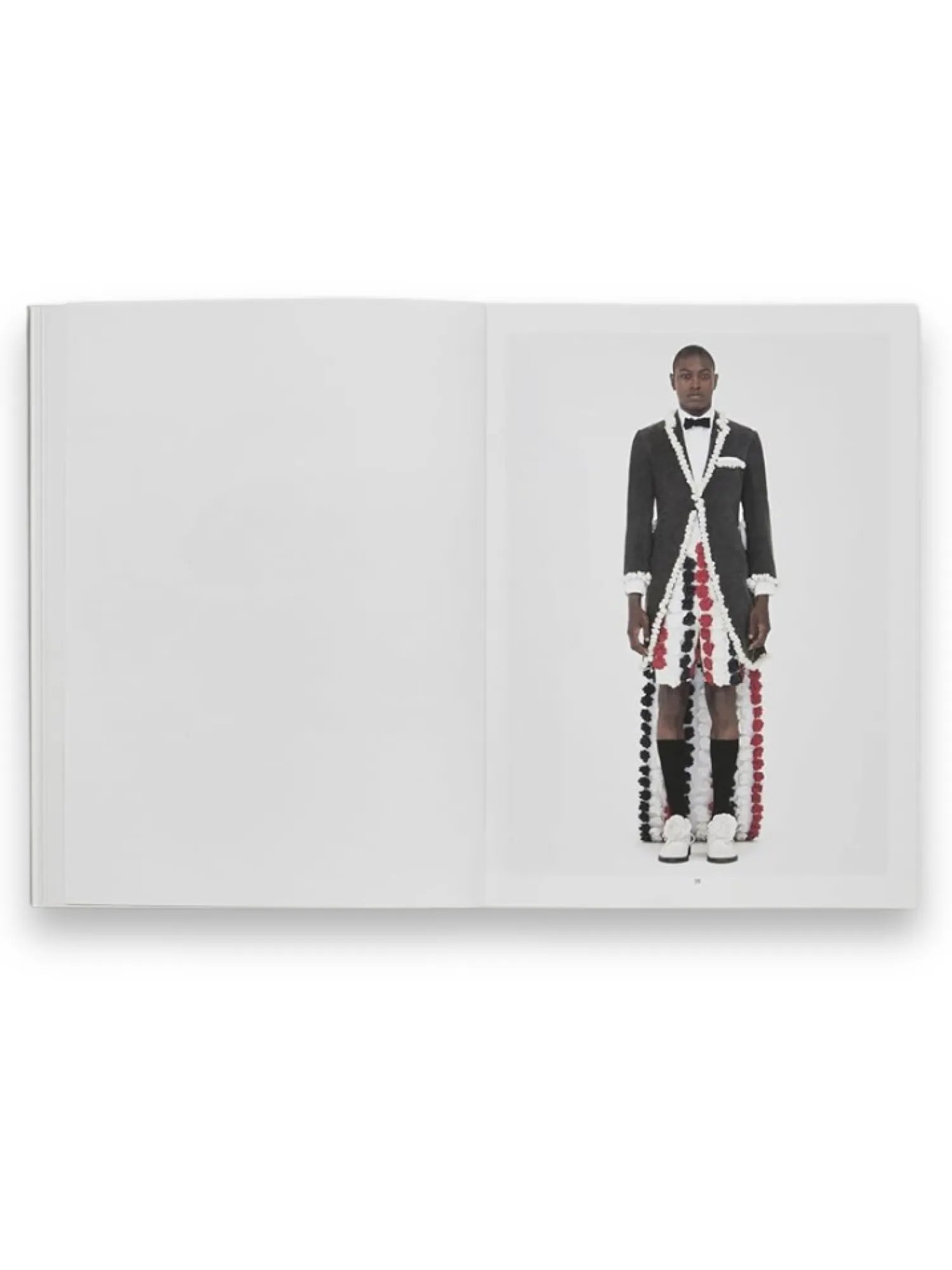 Book Thom Browne, an open fashion book revealing a striking editorial image of a model in a unique gray tuxedo jacket with a cascading red, white, and black pom-pom train. This visually engaging book is perfect for fashion enthusiasts and students interested in avant-garde design and style.