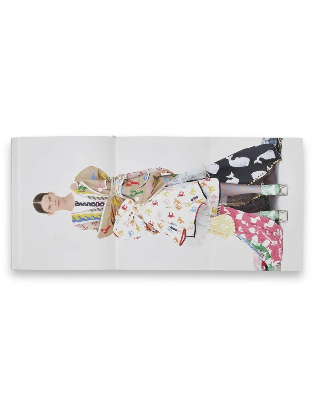 Book Thom Browne, an open fashion book revealing a vibrant spread with a model wearing layered, playfully patterned clothing, including whales, crabs, and lobsters, on a crisp white background. This collectible fashion book is perfect for Thom Browne enthusiasts and fashion history buffs.