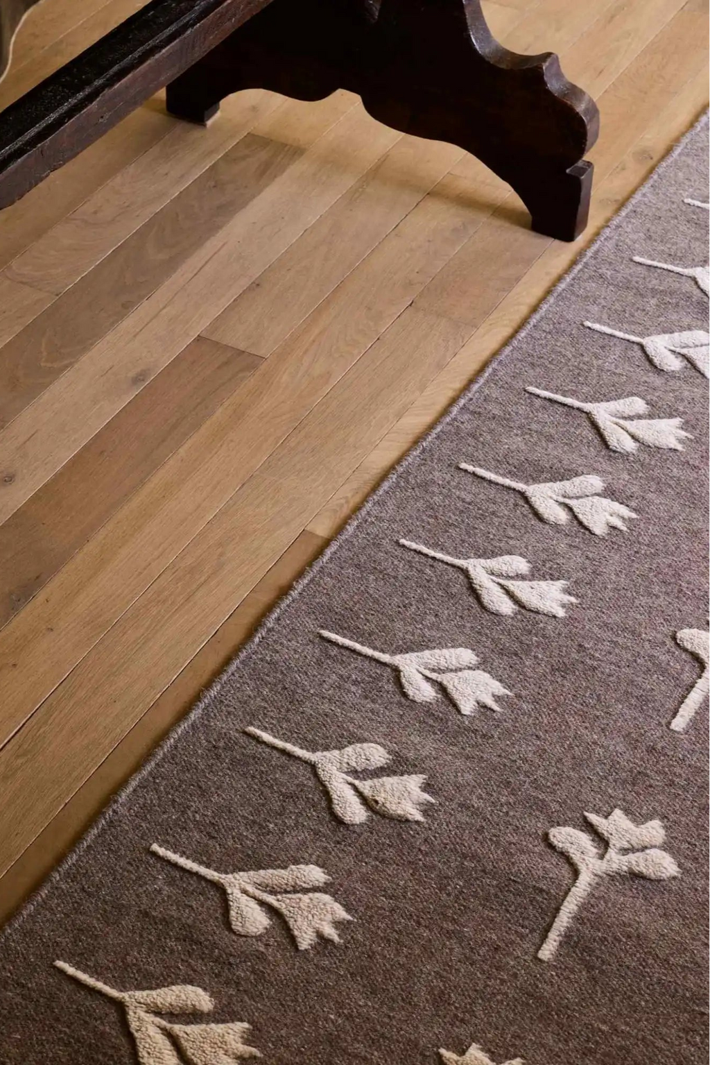 Cappelen Dimyr Colonnade No.09 Rug, a hand-tufted wool area rug featuring a muted brown base with raised, cream-colored organic botanical motifs that create a striking textural contrast. This artisan-crafted natural wool rug brings a cozy, organic modern aesthetic to any space. Perfect for a Scandinavian living room, contemporary bedroom, or rustic entryway.