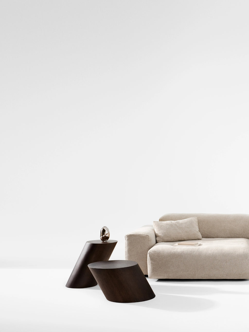 NORR11 Tilt Side Table, a modern minimalist side table crafted from dark brown solid wood, featuring a unique sculptural design with two distinct, angled conical forms that create a dynamic silhouette and smooth matte finish. This contemporary dark oak accent table is perfect for adding an organic modern touch to living rooms or as a unique bedside table in minimalist bedrooms.