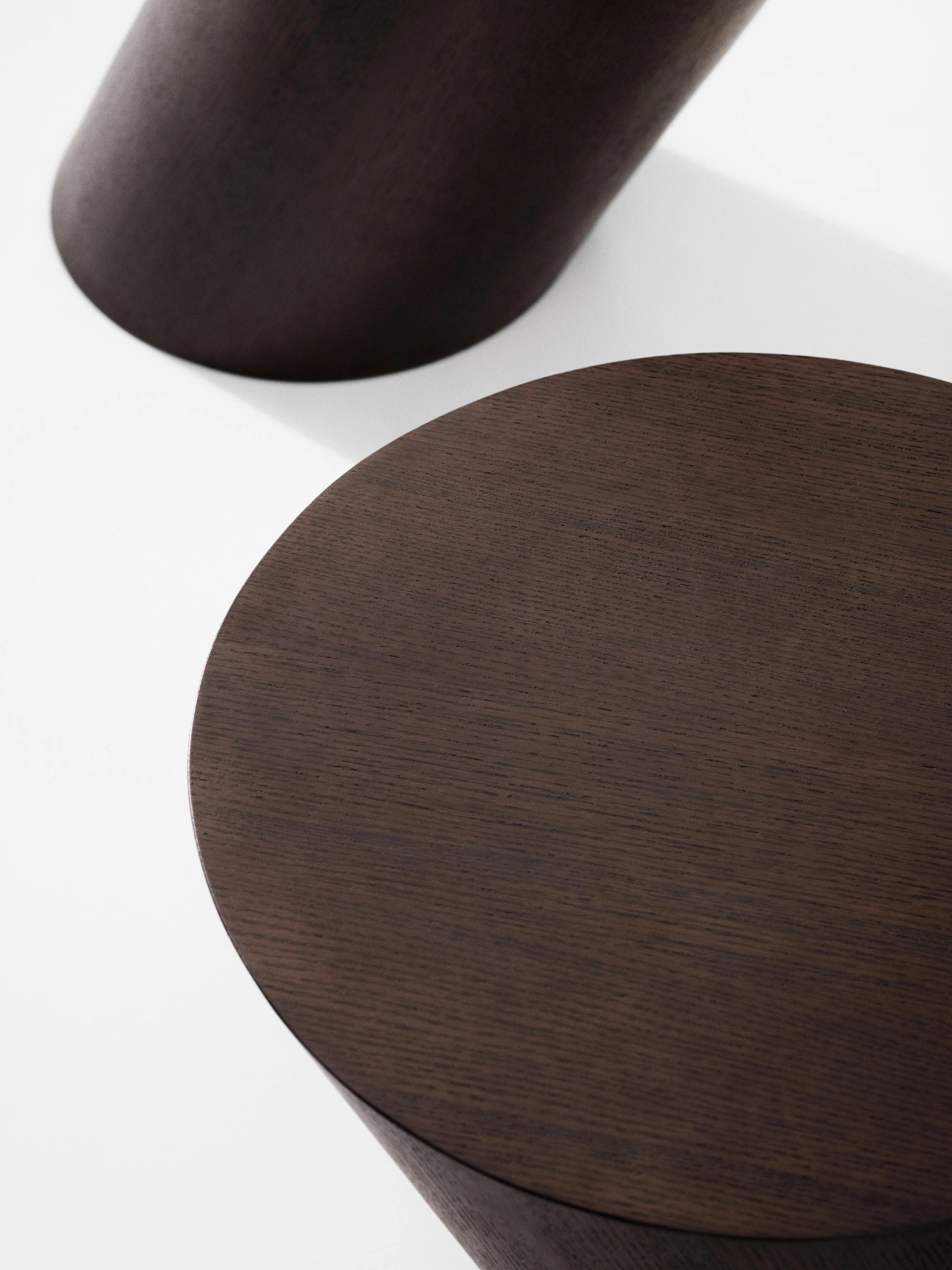 NORR11 Tilt Side Table, a dark brown solid wood side table featuring a rich espresso finish with visible wood grain and a distinctive tilted cylindrical base supporting a round tabletop.