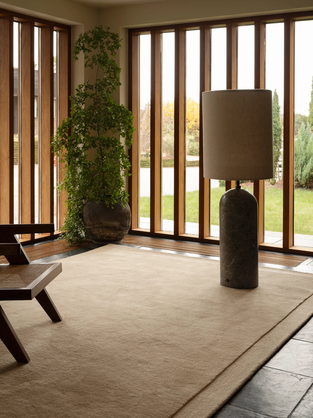Tinted Objects Louis Wool Rug, a plush hand-knotted wool area rug in a natural beige color with a subtle, textured border and soft, inviting pile. This minimalist, organic modern rug is perfect for adding warmth to contemporary living rooms or Scandinavian bedrooms.