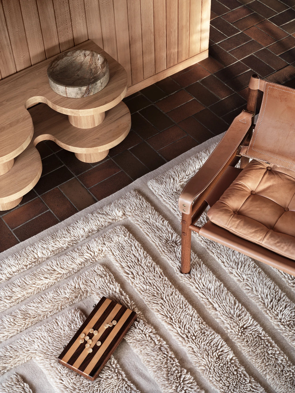 Tinted Objects Kask Wool Rug, a luxurious cream-colored textured area rug with alternating stripes of plush shag and flat weave. This stylish and comfortable floor covering is perfect for adding warmth and sophisticated design to modern living spaces.