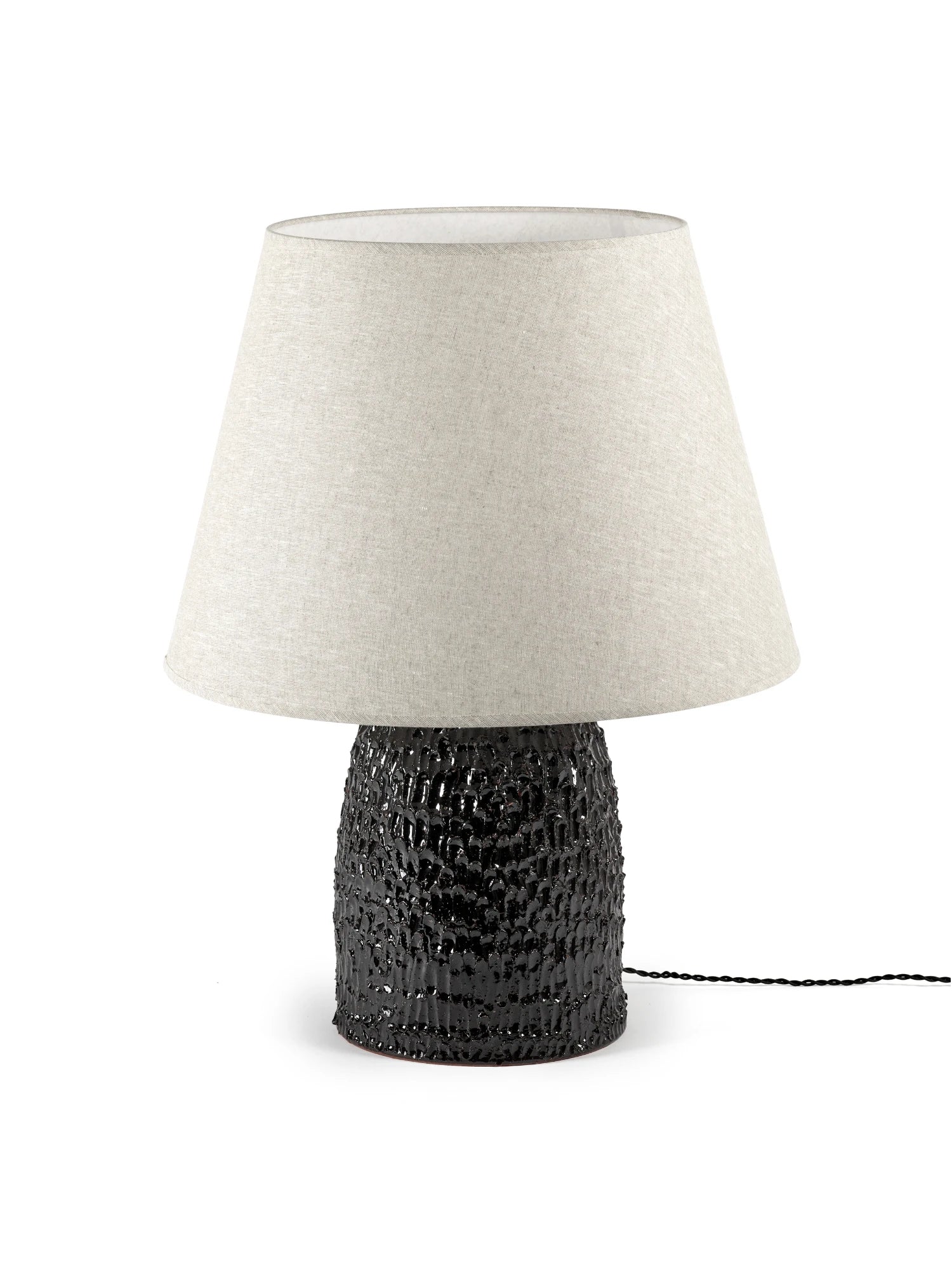 Table lamp with textured black base and white shade on a white background