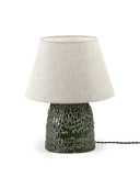 A medium-sized Tronco ceramic table lamp with a dark green, highly textured, glossy base and a conical, neutral white/beige fabric lampshade. The lamp is photographed on a white background with a black electrical cord extending to the right.