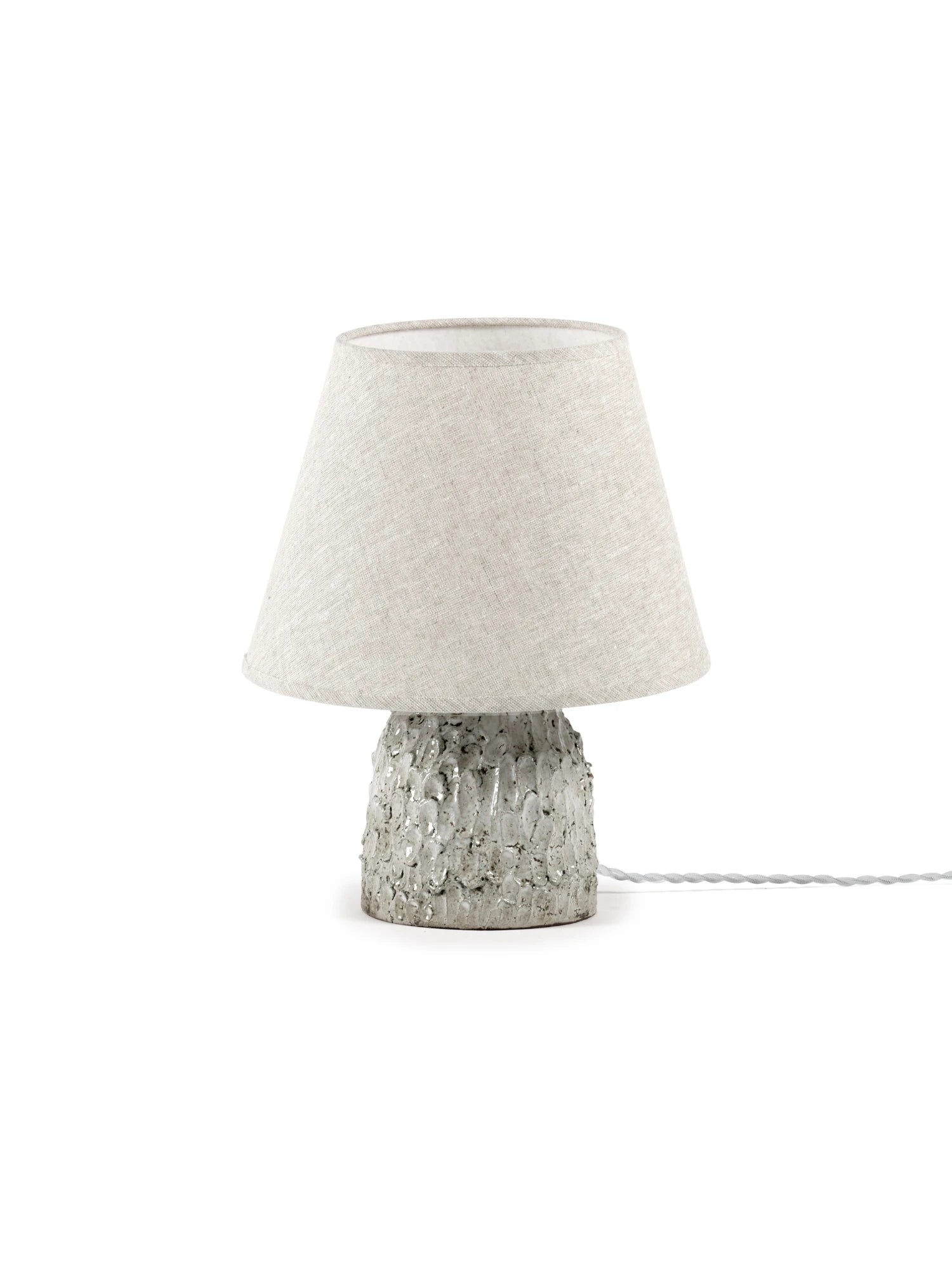 Table lamp with textured concrete base and light gray fabric shade on a white background