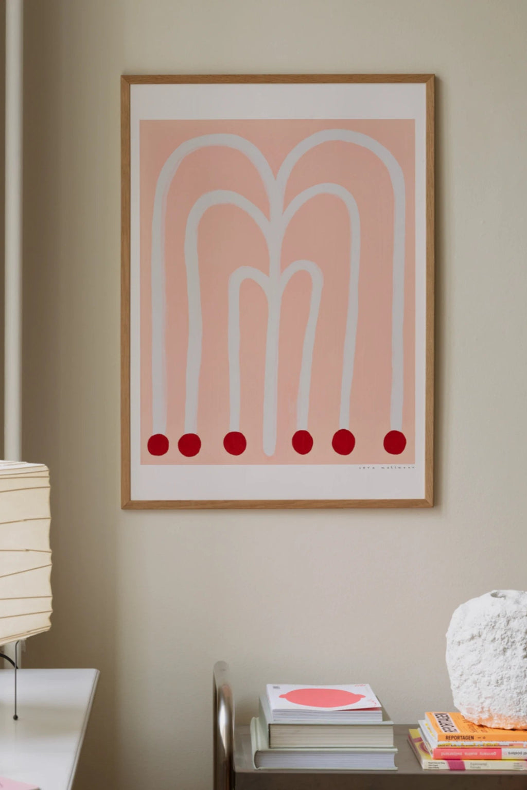 The Poster Club Grosse Blume, an abstract art print featuring a soft pale pink background with bold white organic arched lines and five vibrant red circles at the base, framed in a light natural oak frame with a white mat. This minimalist and playful contemporary wall art is ideal for Scandinavian bedrooms, modern living rooms, or a creative gallery wall.