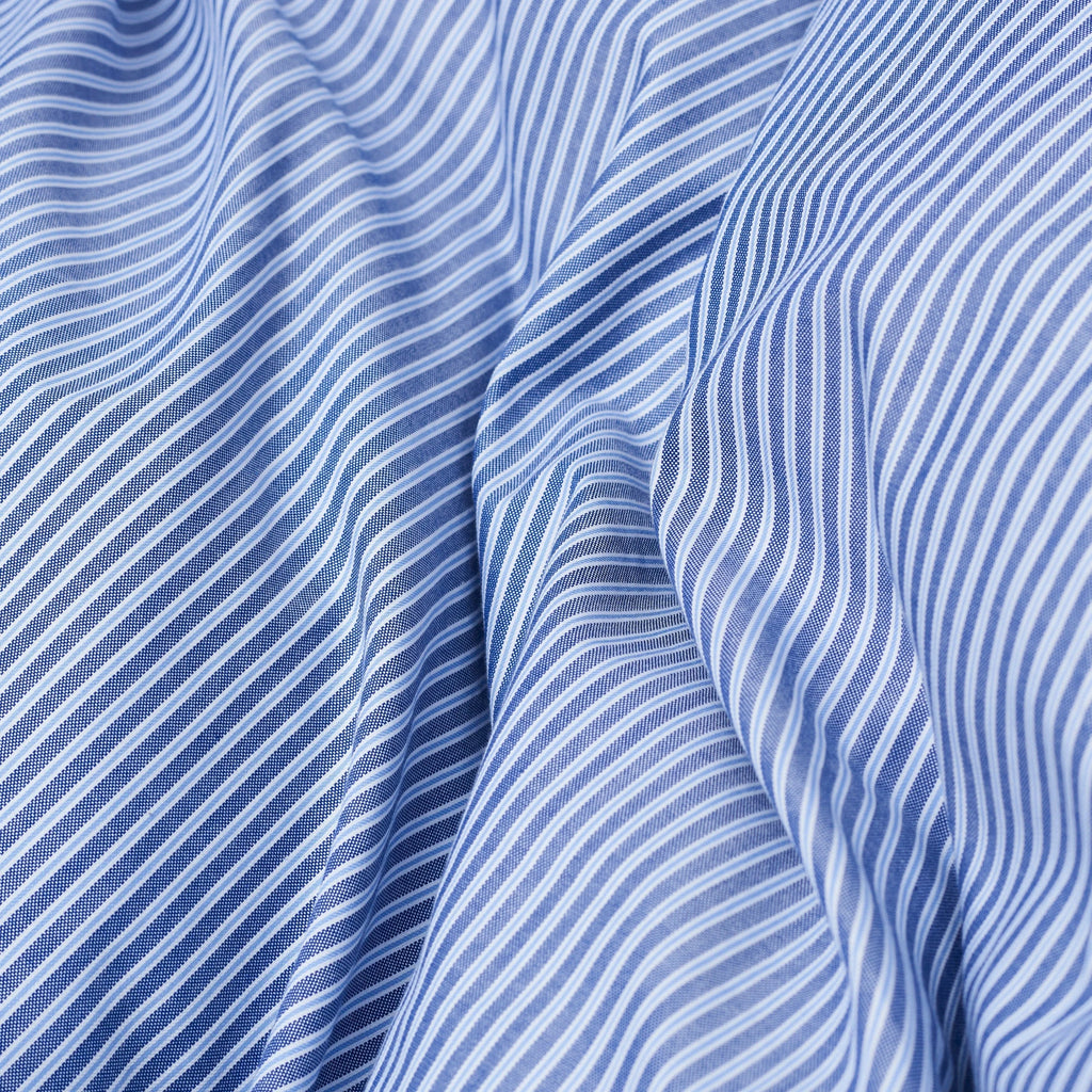 Magniberg Wall Street Duvet Cover - Stripe Dark Blue Oxford, a classic dark blue and white striped Oxford cotton duvet cover featuring a crisp, finely woven texture and soft drape. This tailored bedding offers a timeless yet contemporary aesthetic, with varying shades of blue and white pinstripes creating a sophisticated pattern. Ideal for elevating modern minimalist or classic bedroom decor with a touch of refined elegance.