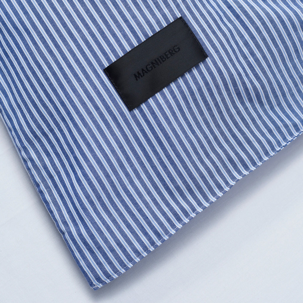 Magniberg Wall Street Pillow Case - Stripe Dark Blue, a sophisticated blue and white striped pillowcase crafted from crisp cotton percale fabric, featuring a classic pinstripe pattern and a subtle woven texture. The deep royal blue and clean white stripes create a tailored, timeless aesthetic. Ideal for adding a refined touch to modern minimalist or classic contemporary bedroom decor.